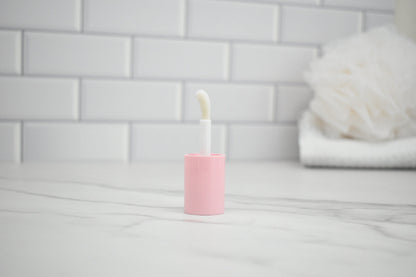 Pink lipgloss lid on a marble counter