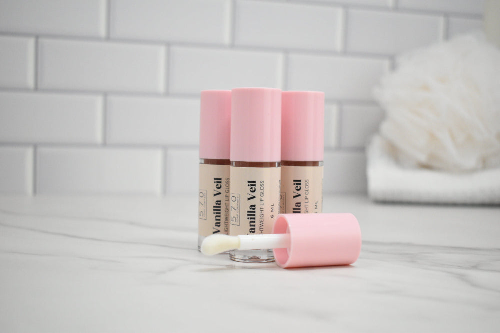 Two Vanilla Veil lip balm tubes with a applicator on a light gray surface.