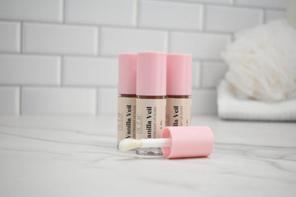 Two Vanilla Veil lip balm tubes with a applicator on a light gray surface.