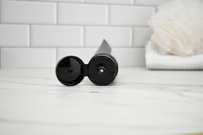 Two black cylindrical objects on a white surface with a tiled wall background