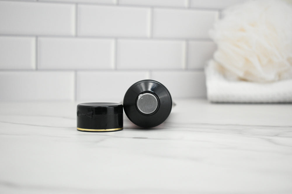 Two black bottle caps on a white surface with a tiled wall background