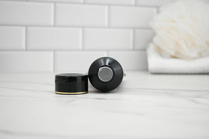 Two black bottle caps on a white surface with a tiled wall background