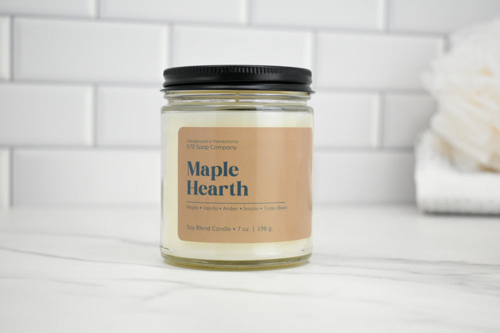 Candle jar labeled 'Maple Hearth' on a white surface with a tiled wall background