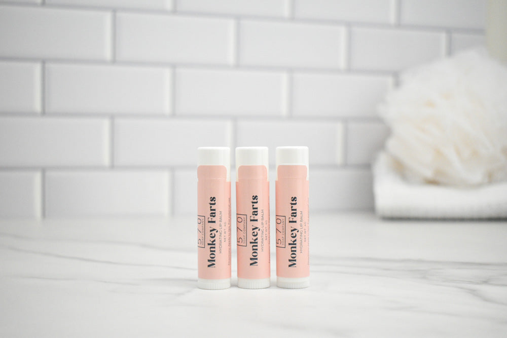 Three lip balm tubes with 'Monkey Farts' branding on a white surface.