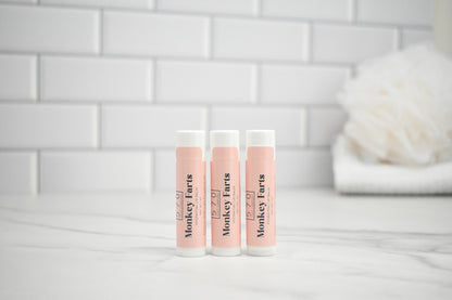 Three lip balm tubes with 'Monkey Farts' branding on a white surface.