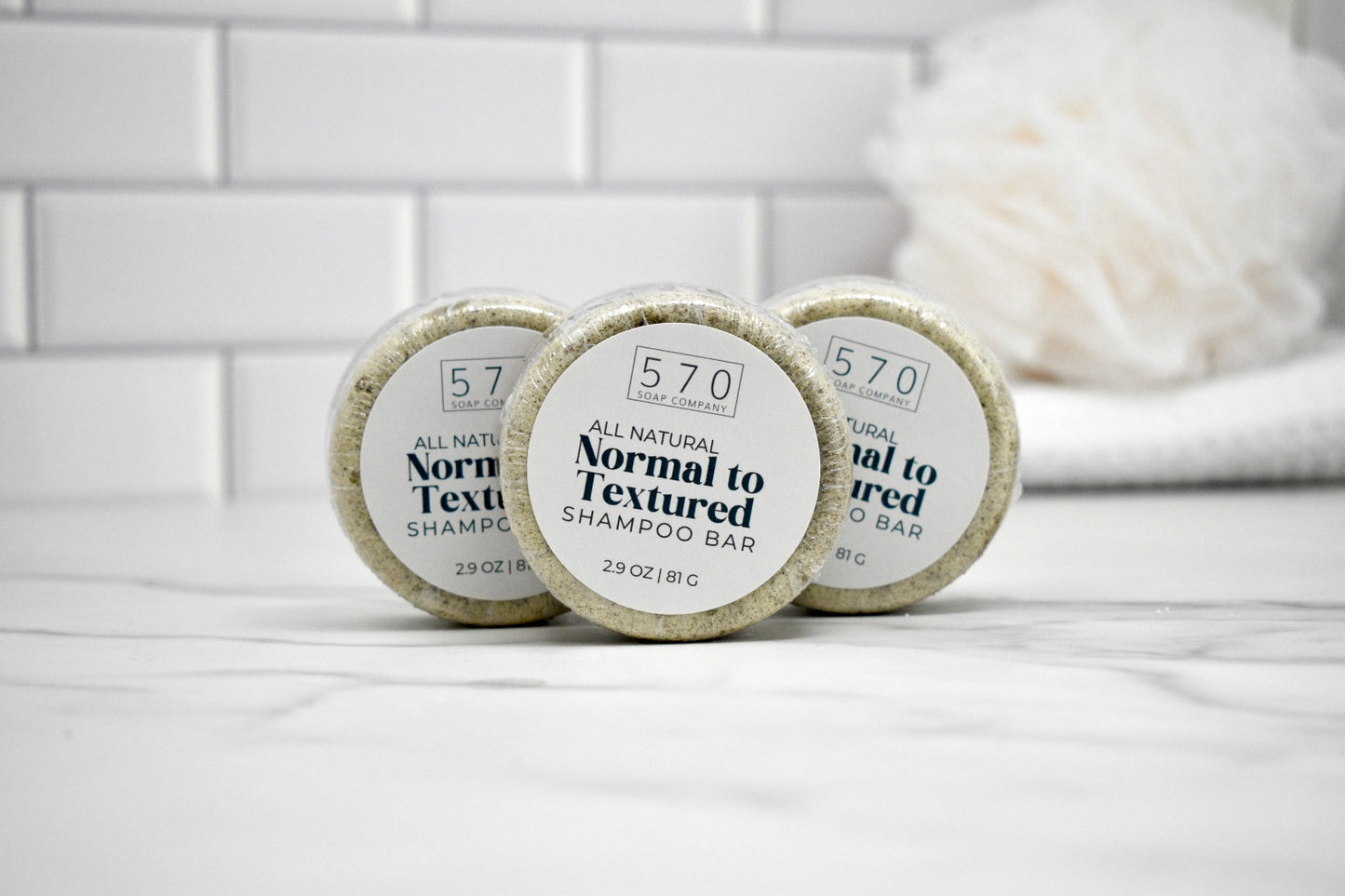 Three shampoo bars labeled '570' on a white surface with a tiled wall background.