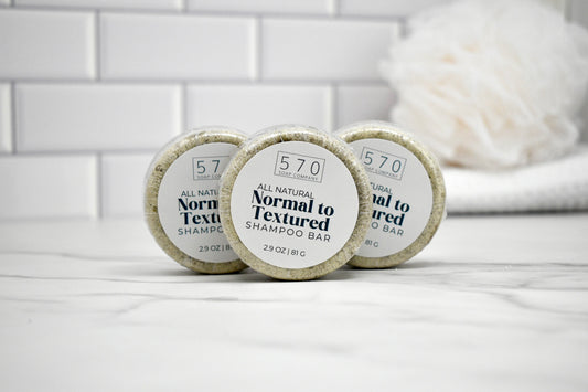 Three shampoo bars labeled '570' on a white surface with a tiled wall background.
