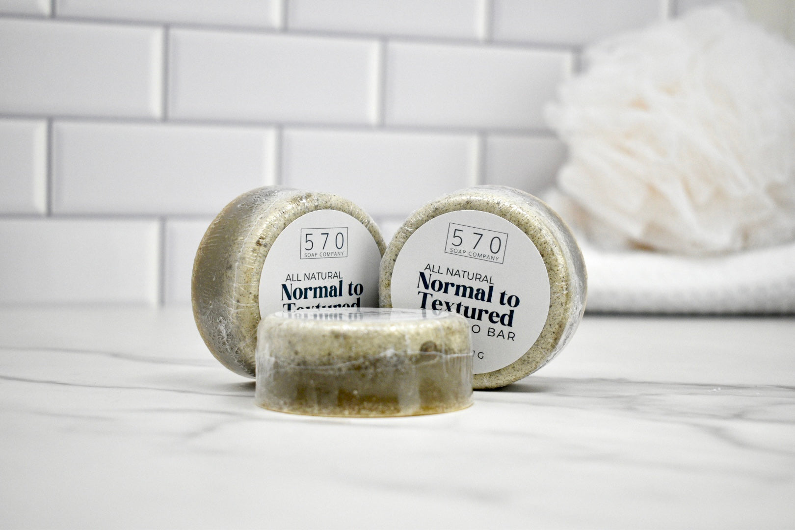 Three soap bars labeled '570' on a white surface with a tiled wall background.
