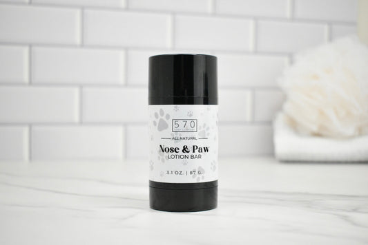 Nose and paw lotion bar with black and white packaging on a white surface.