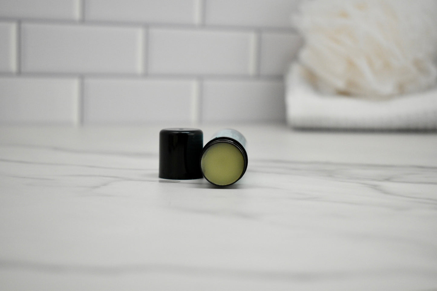 Menthol Balm container open on a white surface with a blurred background