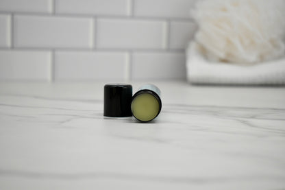 Menthol Balm container open on a white surface with a blurred background