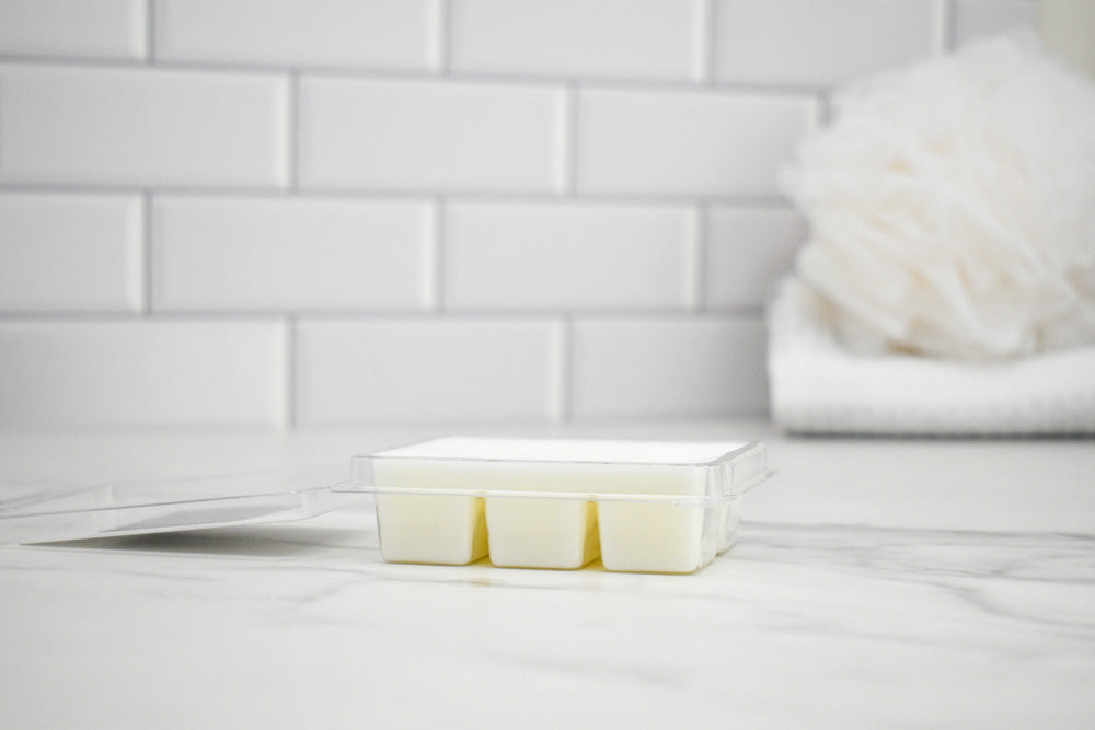 Wax melt clamshell open on a white surface with a tiled wall background