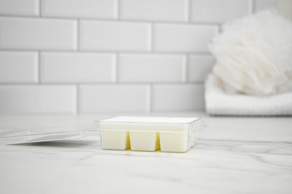 Wax melt clamshell open on a white surface with a tiled wall background