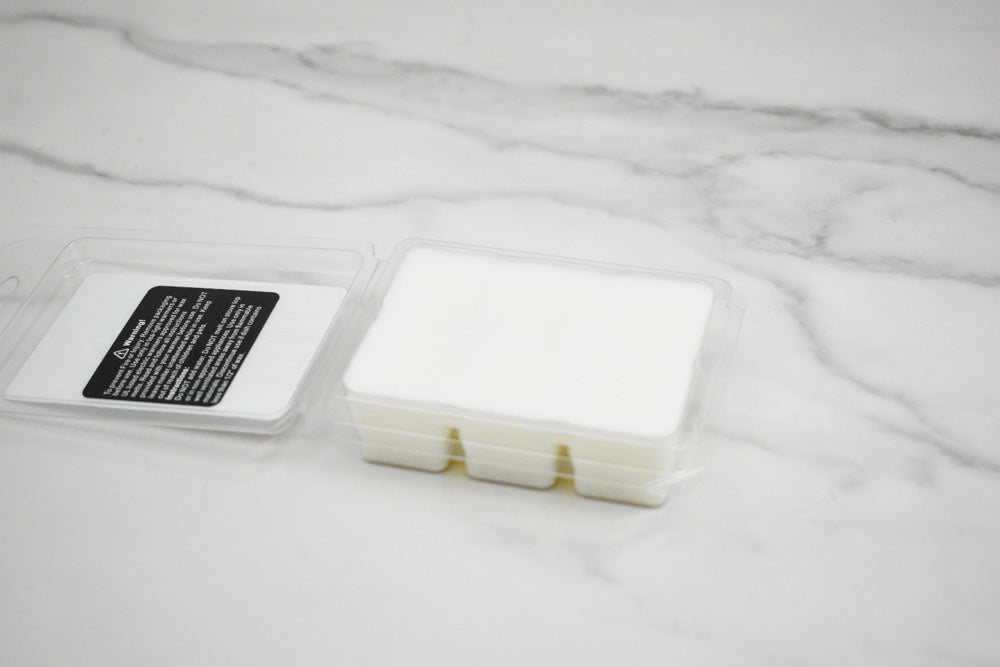 White wax melt container with a label on a marble surface