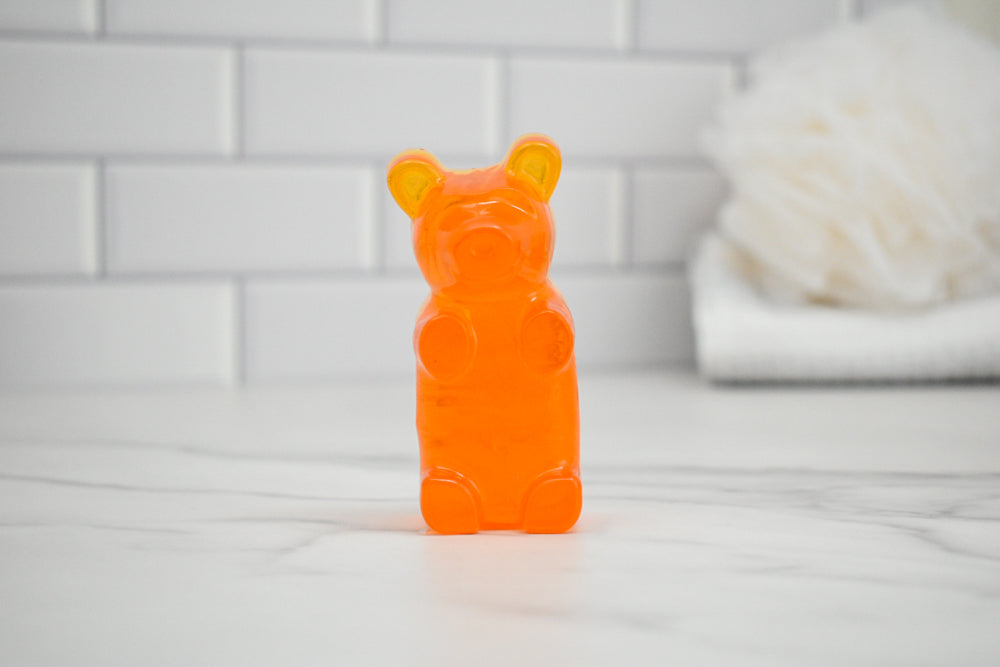 Orange gummy bear-shaped soap on a white surface with a tiled wall background