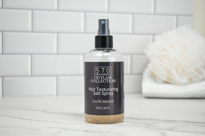Bottle of 570 Outlaw Collection Hair Texturizing Salt Spray on a bathroom counter.