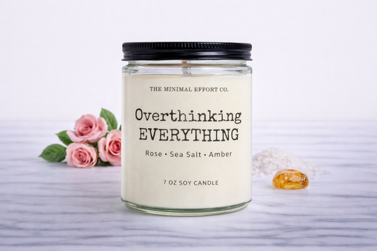 Candle with 'Overthinking EVERYTHING' text and floral decorations on a light background
