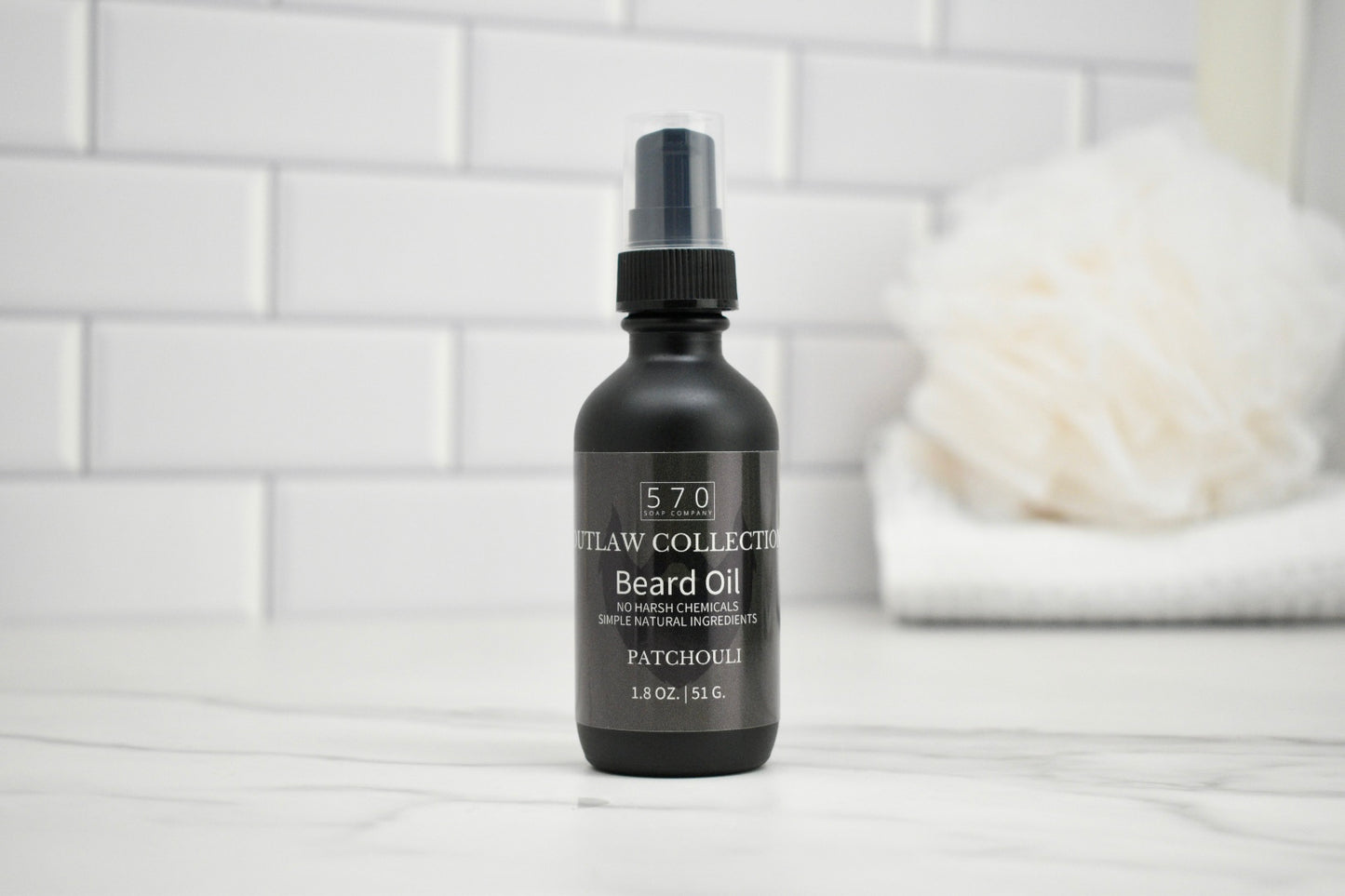 Black beard oil bottle with label on a white surface and tiled wall background