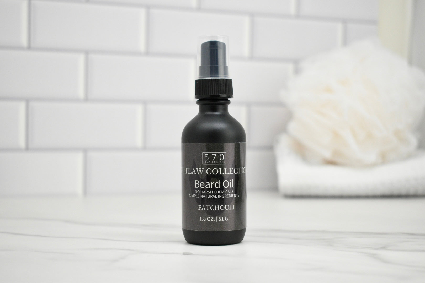 Black beard oil bottle with label on a white surface and tiled wall background
