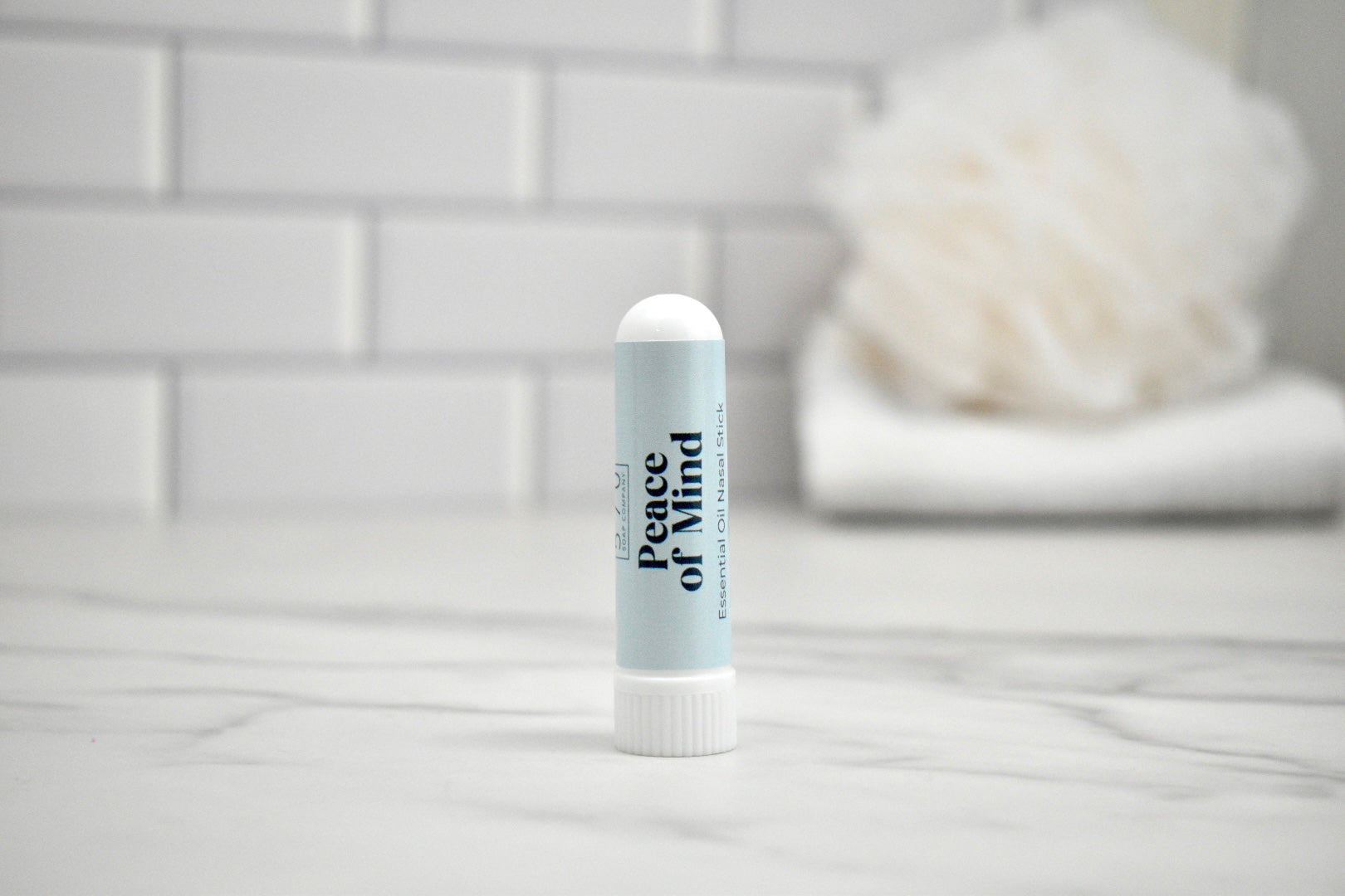 Nasal stick labeled 'Peace of Mind' on a bathroom counter with a blurred background