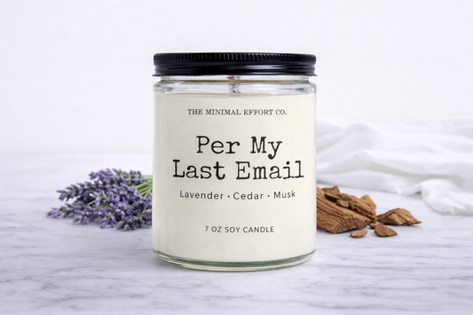 Scented candle labeled 'Per My Last Email' with lavender, cedar, and musk notes on a marble surface.
