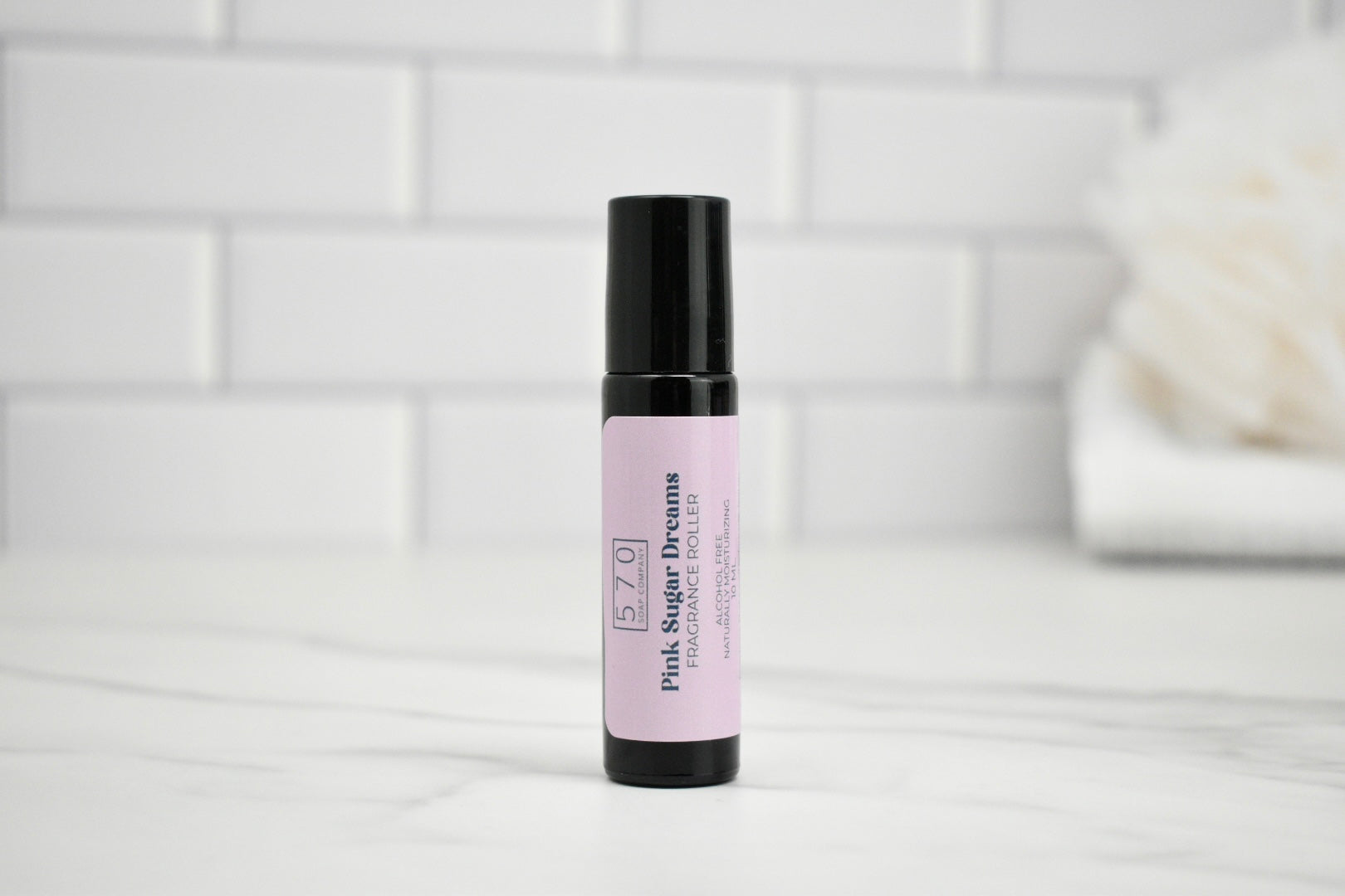 Skincare serum bottle with pink label on a white surface