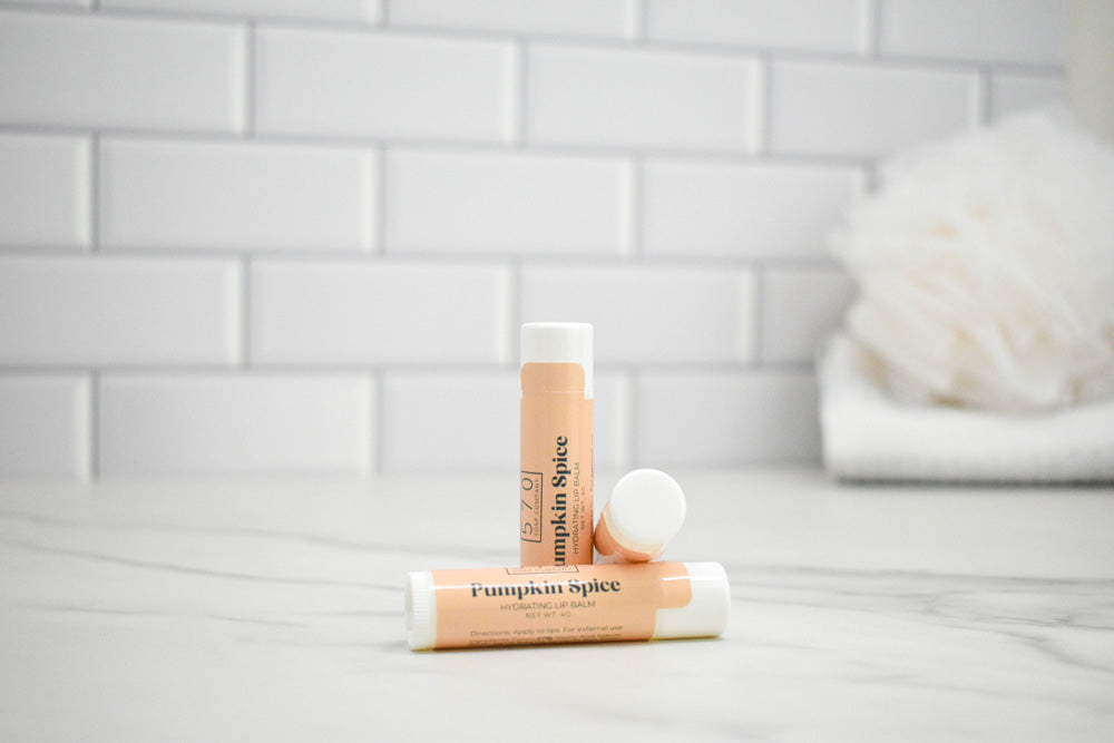Three lip balm tubes with 'Pumpkin Spice' flavor on a bathroom counter.