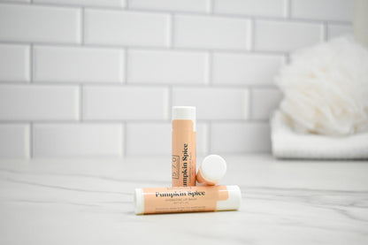 Three lip balm tubes with 'Pumpkin Spice' flavor on a bathroom counter.
