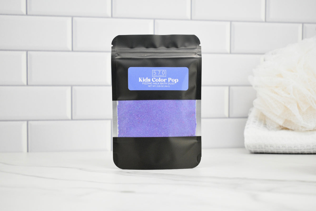 Black packaging with purple powder on a white tiled background
