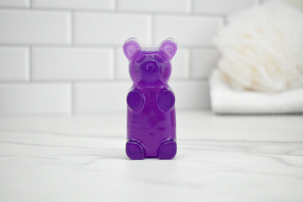 Purple gummy bear-shaped soap on a white surface with a tiled wall background