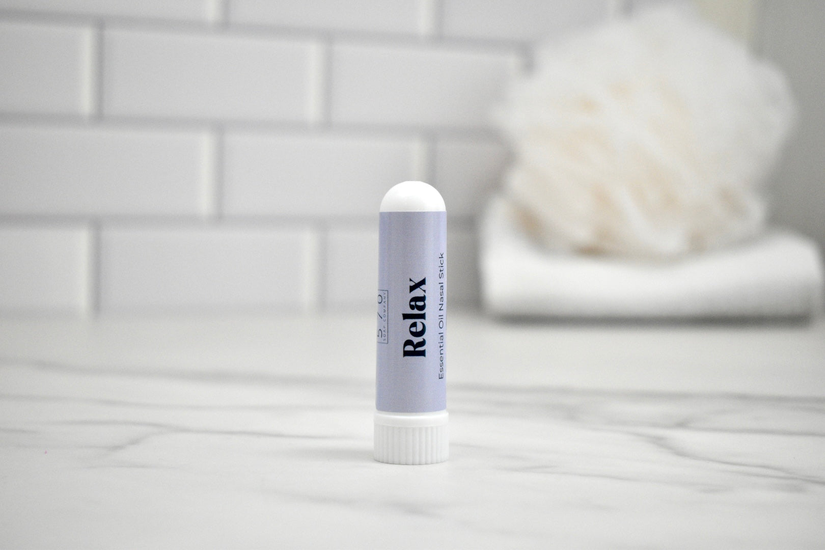 Nasal Stick labeled 'Relax' on a bathroom counter with a blurred background