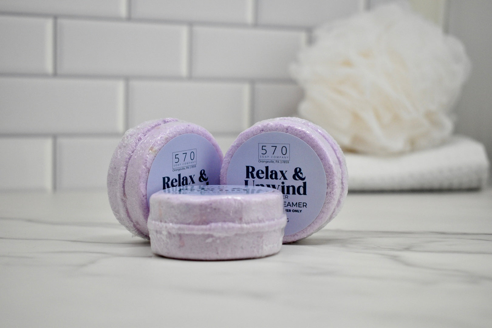 Three lavender bath bombs with '570' branding on a bathroom counter.