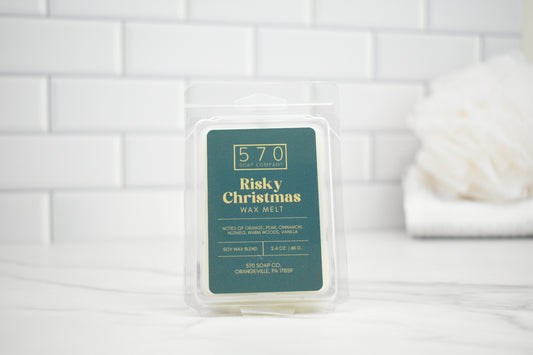 Wax melt packaging labeled 'Risky Christmas' on a white tiled background