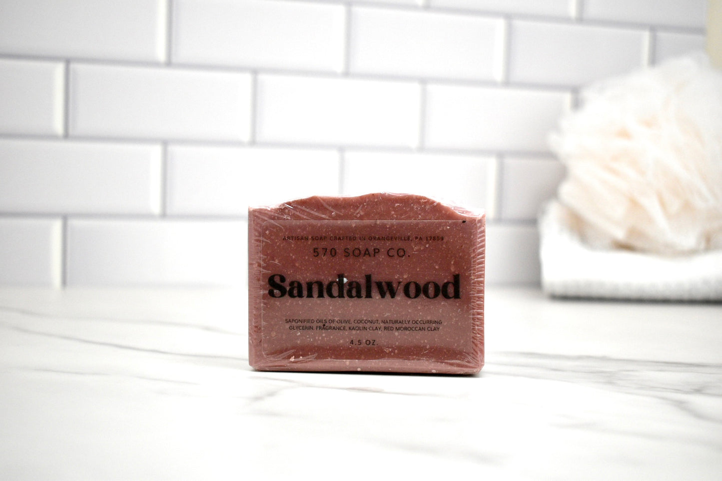 Bar of sandalwood soap from Sandalwood Soap Co on a white surface with a tiled wall background.