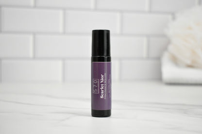 Purple skincare serum bottle with black cap on a white surface with a light gray tiled wall background