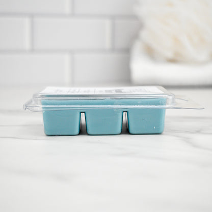 Clear plastic mold with blue wax cubes on a white surface