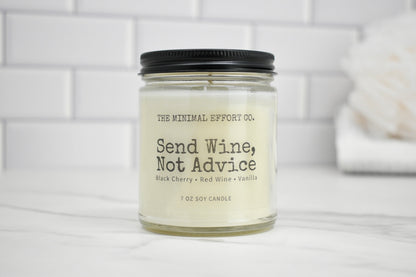 Candle jar labeled 'Send Wine, Not Advice' on a white surface with a tiled wall background.