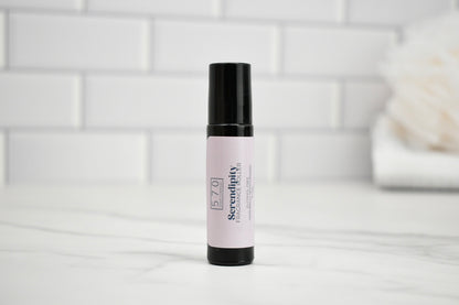 Skincare serum bottle with pink label on a white surface with a tiled wall background