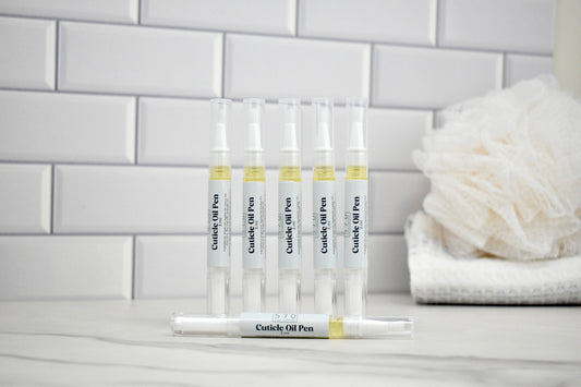 Set of cuticle oil pens on a stand with a white tiled wall background