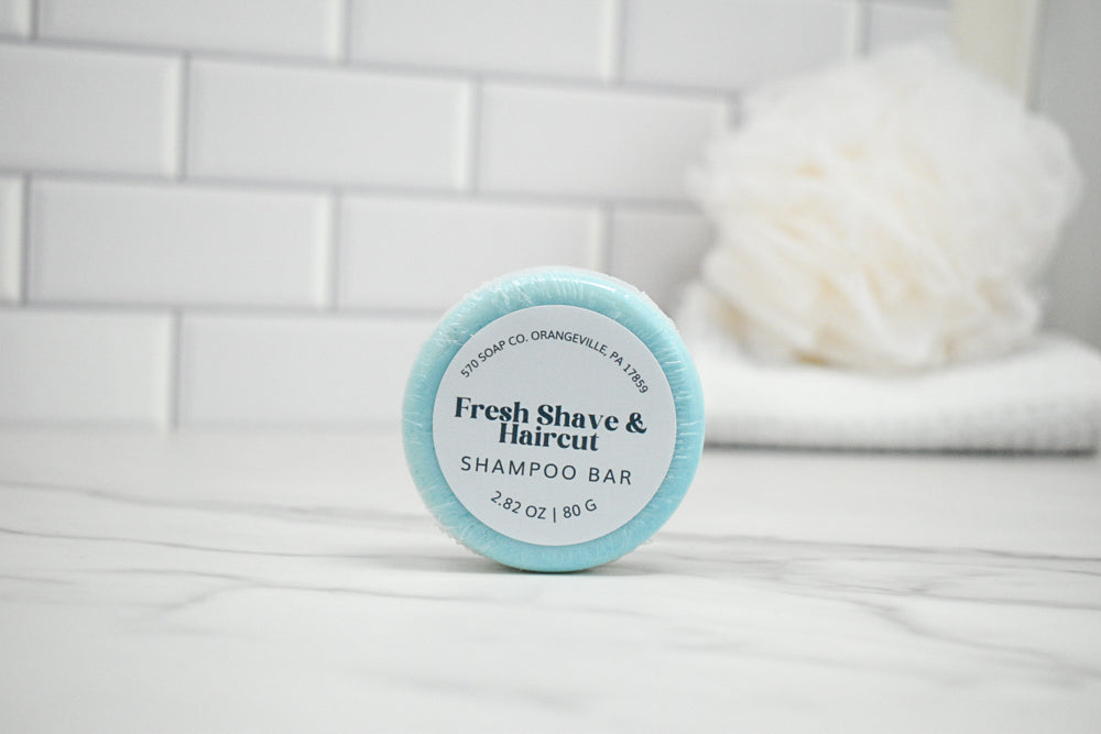 Shampoo bar with 'Fresh Shave & Haircut' label on a bathroom shelf.
