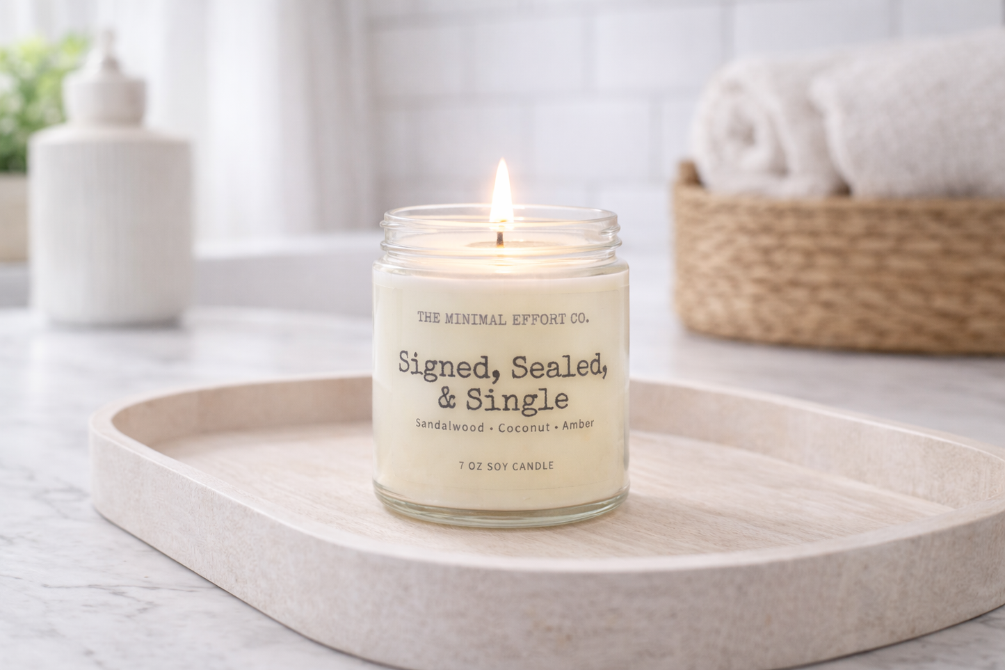 Candle labeled 'Signed, Sealed, & Single' on a white surface with a blurred background