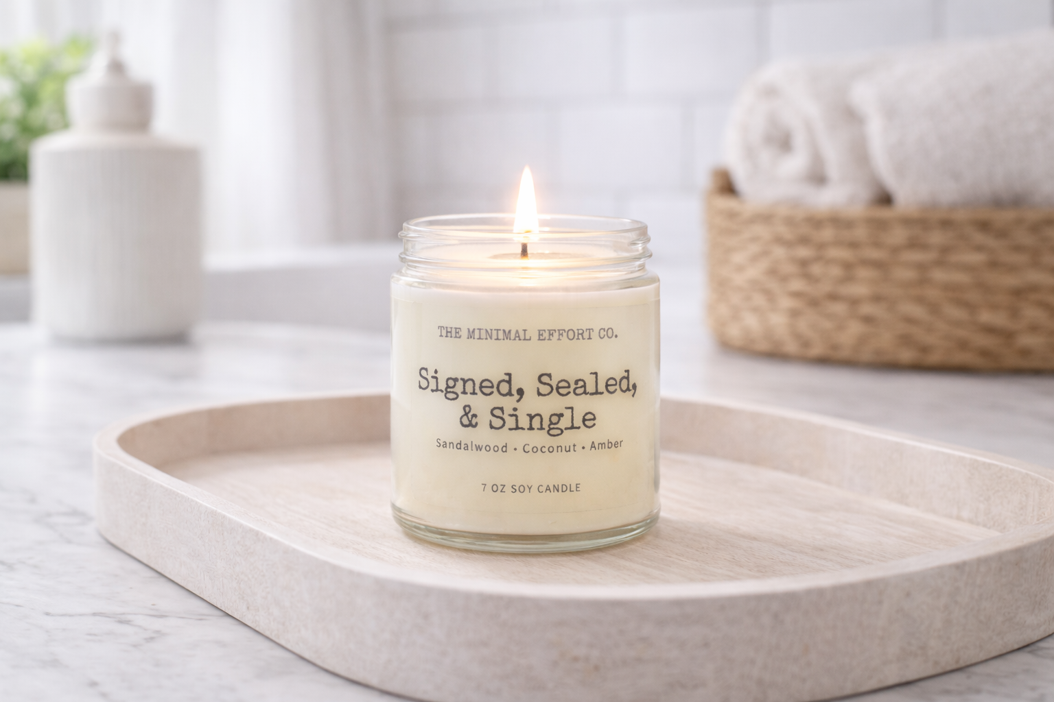 Candle labeled 'Signed, Sealed, & Single' on a white surface with a blurred background