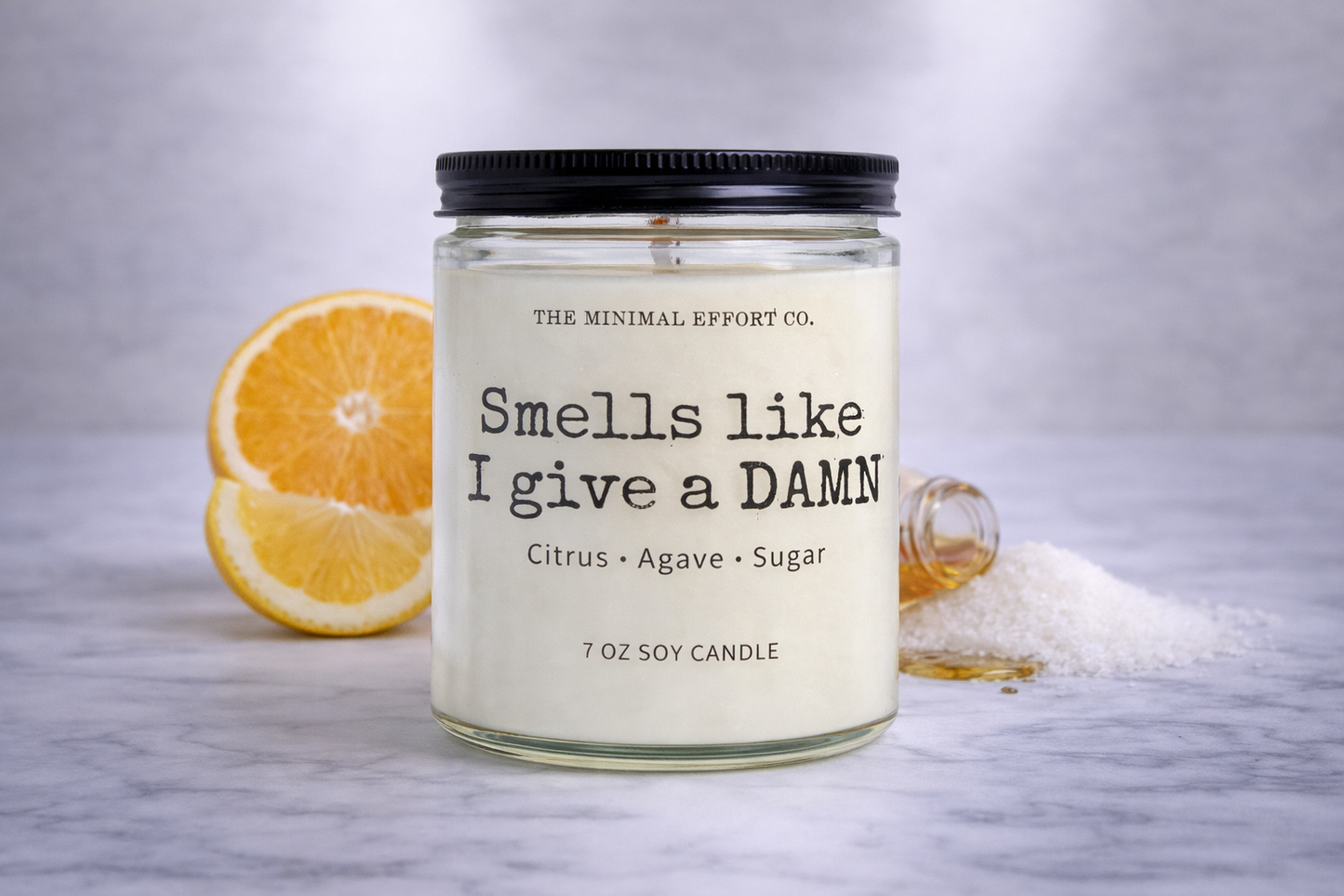Candle jar labeled 'Smells like I give a DAMN' with oranges and sugar on a gray background