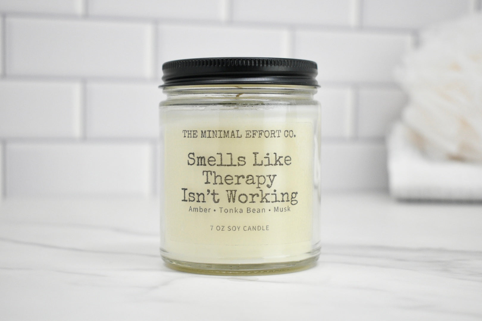Candle jar with 'Smells Like Therapy Isn't Working' text on a white background