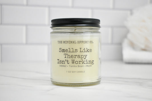 Candle jar with 'Smells Like Therapy Isn't Working' text on a white background