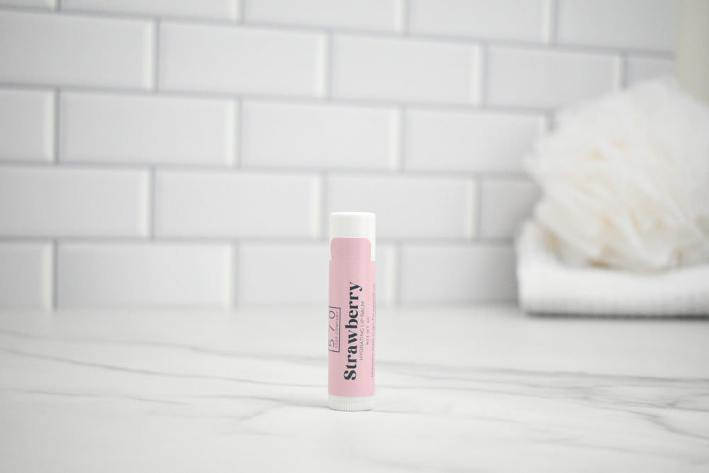 Lip balm with pink packaging on a white surface against a tiled wall background
