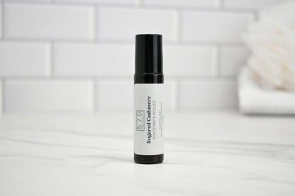 Skincare serum bottle with black cap on a white surface against a light tiled wall background