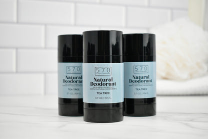 Three bottles of 570 Natural Deodorant on a white surface with a tiled wall background.