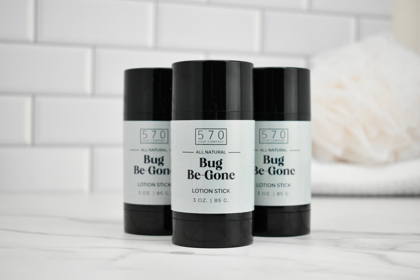 Three 'Bug Be Gone' lotion sticks with black and white labels on a white surface.