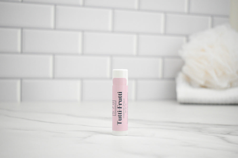 Pink lip balm tube on a white surface with a tiled wall background